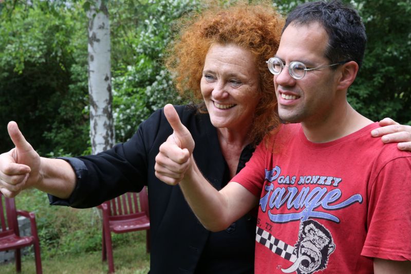 Daumen hoch zeigen eine Betreuerin und ein Lebensorte-Mitbewohner im roten Shirt, lachend schauen sie in dieselbe Richtung. Aufnahme bei einem Sommerfest