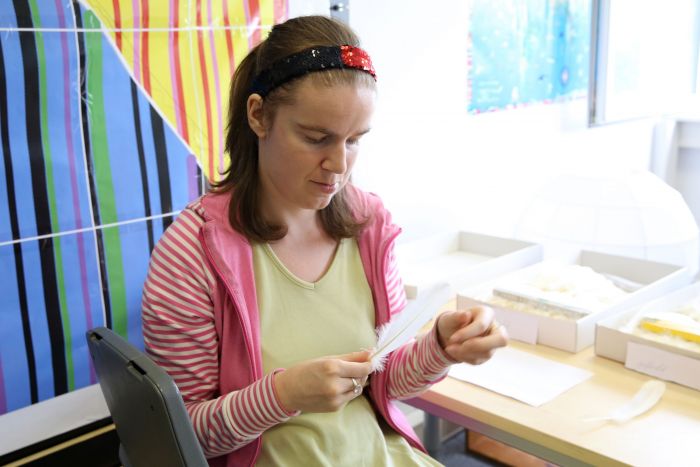 Mitarbeiterin unserer Designwerkstatt hält eine weiße Feder in der Hand