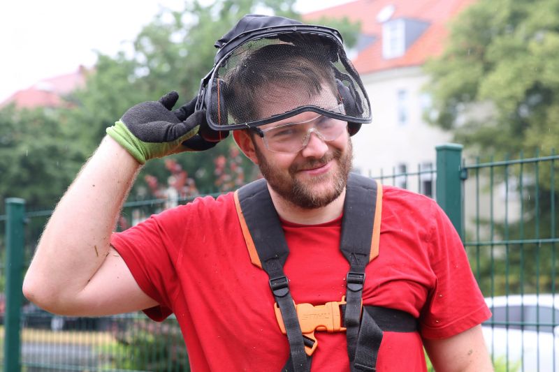 Ein Problemlos-Mitarbeiter nimmt seinen Gehörschutz ab und lächelt in die Kamera