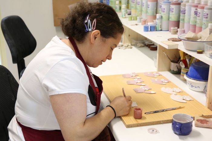 eine Mitarbeiterin in unserer Keramikwerkstatt bemalt Anhänger aus Keramik