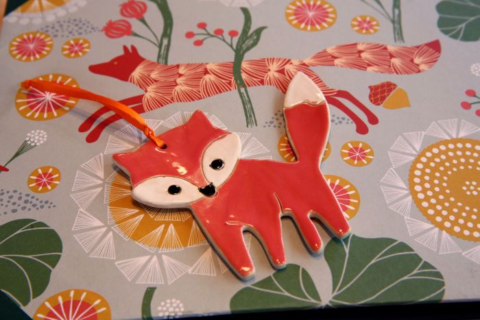 Fuchsanhänger aus Keramik auf kunstvollem Design-Papier liegend