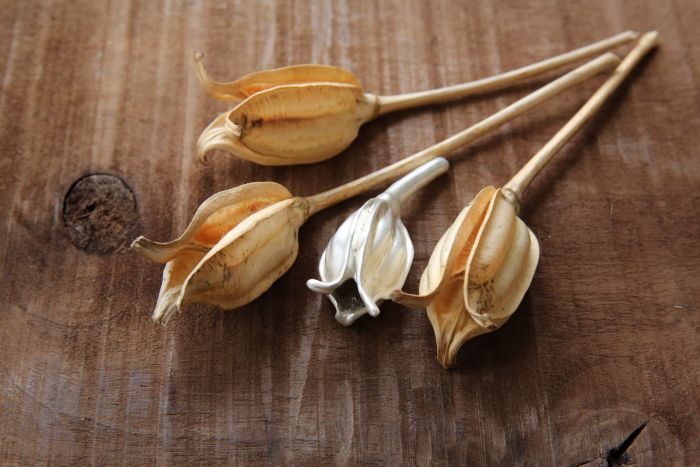 Kunstobjekte aus Silber, Design-Schmuck, der nach der Natur erstellt wurde - fertiges Designobjekt mit Vorlage auf einem Holz-Hintergrund liegend