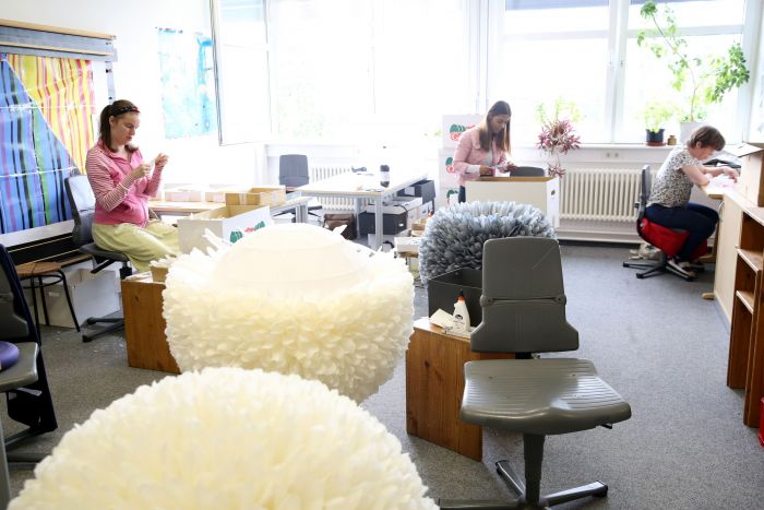Arbeiterinnen aus unserer Kunstwerkstatt arbeiten an Leuchten aus Federn