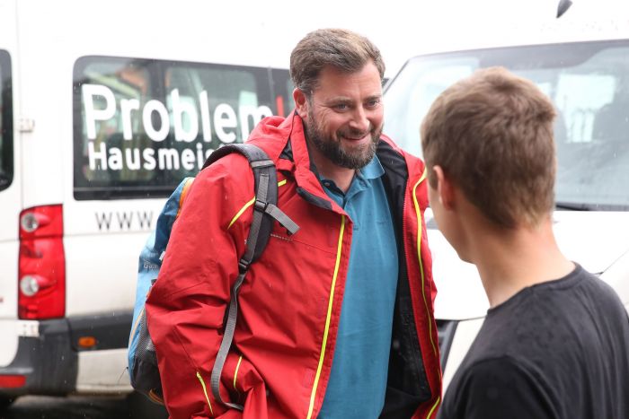 Zwei junge Mitarbeiter der Problemlos Hausmeisterei unterhalten sich und lächeln sich an