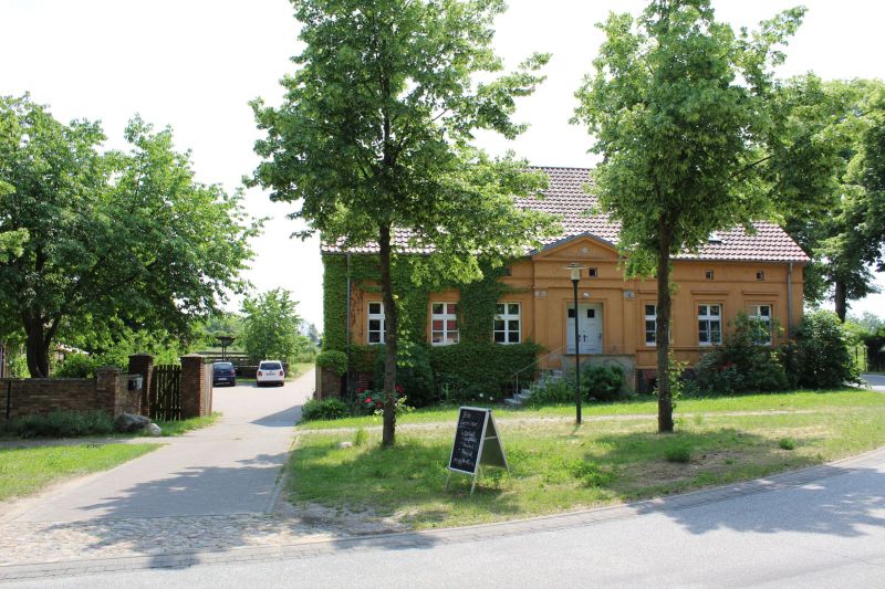 Unser Standort in Rohrlack mit Haus und Kundenstopper, Bäume im Vordergrund und Einfahrt in den Hof