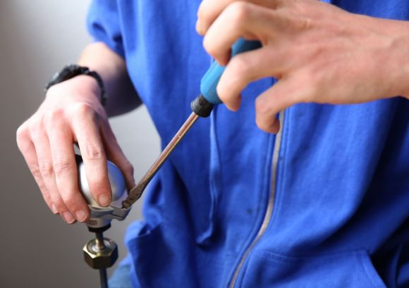 Nahaufnahme von Händen eines Mitarbeiters aus unserer Werkstatt, Montage mit Schraubenzieher