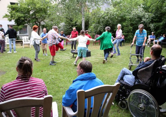 Bewohner der LebensOrte tanzen im Kreis beim Sommerfest